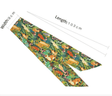 A flat, unfolded green headband with a jungle animal and botanical print, showing dimensions of 9 cm width and 103 cm length.