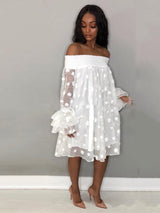 Front view of a woman in a white off-the-shoulder polka dot dress