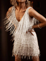 Close-up of a woman in a white sequined fringe mini dress, hands on hips.