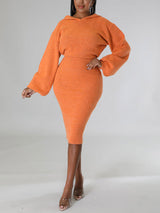 Woman wearing an orange hooded knit sweater and pencil skirt set, front view.