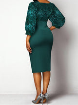 Back view of a woman wearing a dark green sequined v-neck bishop sleeve sheath dress with a pencil skirt and side slit.