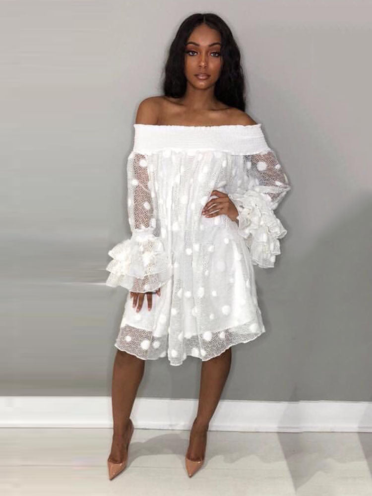 Woman wearing a white off-the-shoulder polka dot dress with ruffled bell sleeves and nude heels