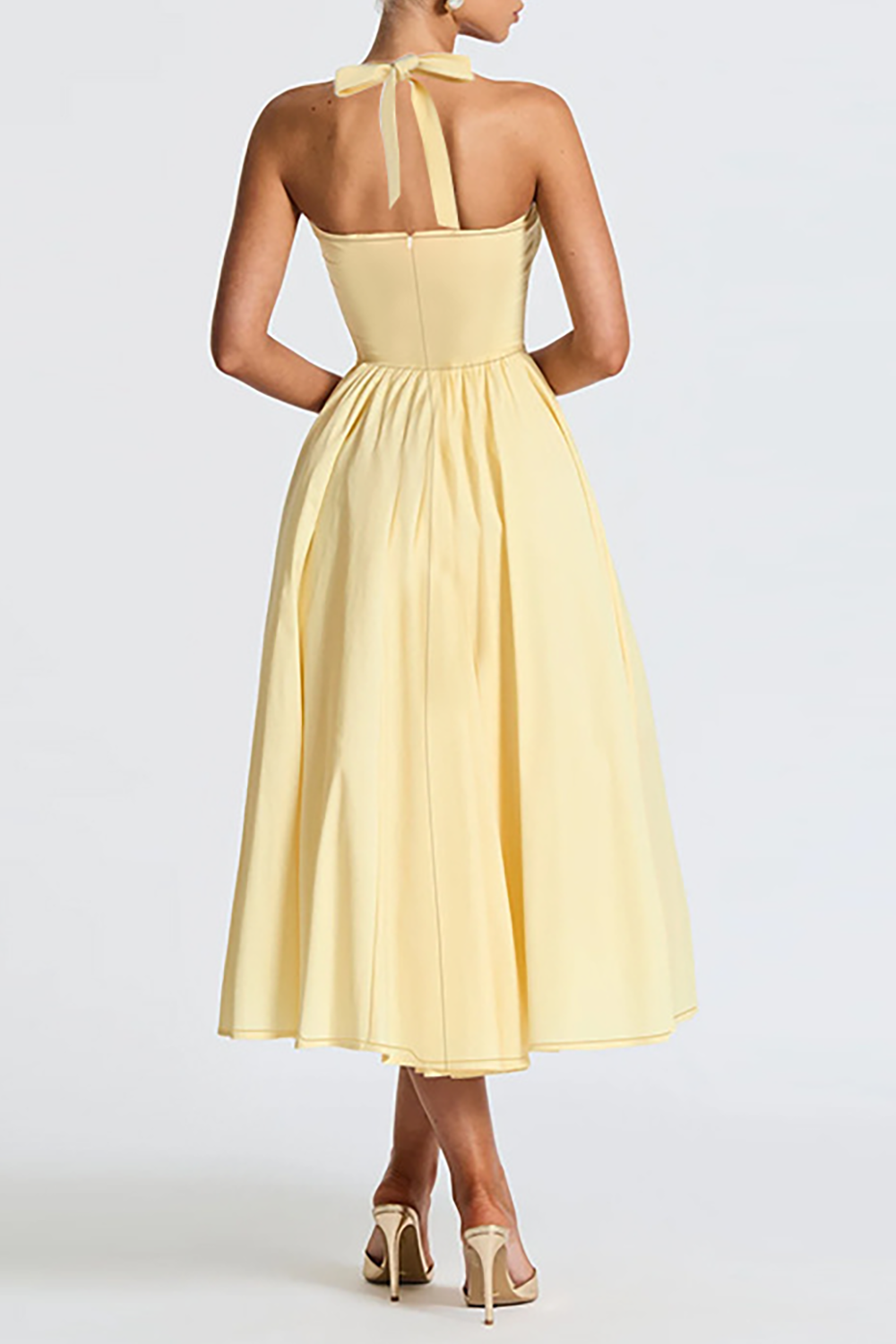 Back view of a pale yellow halter midi dress with a fitted bodice and full skirt.