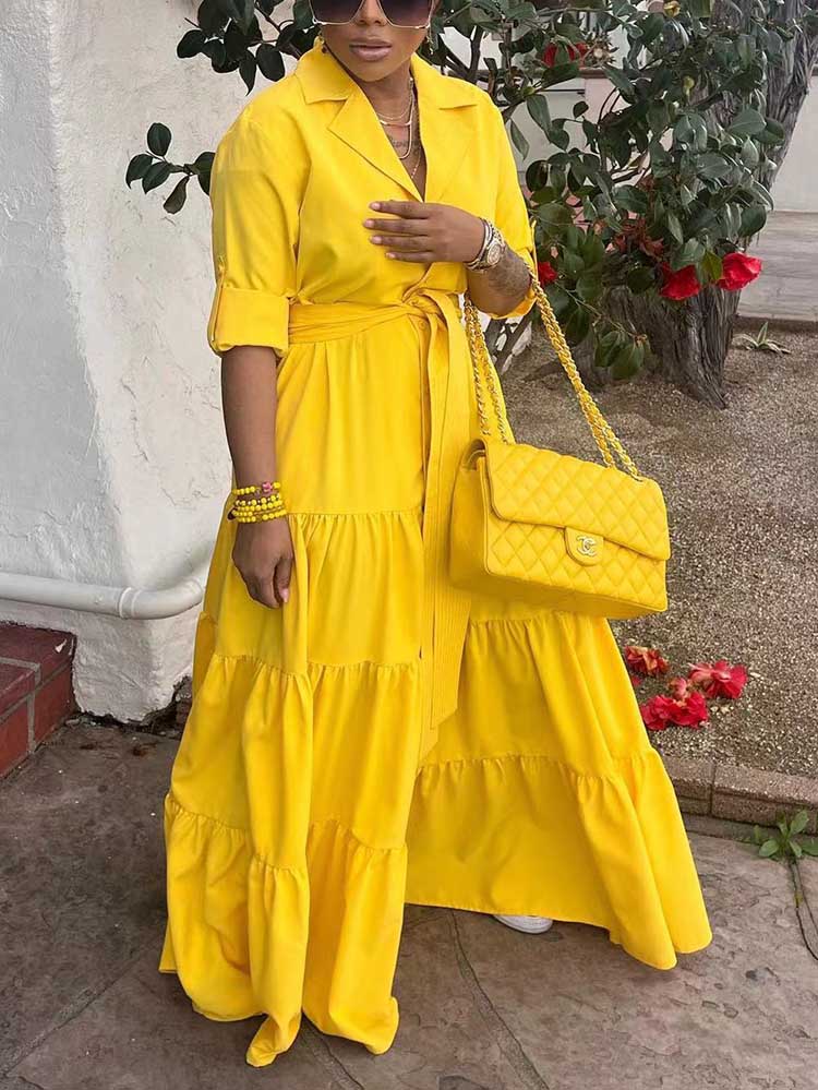Woman in a yellow tiered maxi dress with a yellow quilted handbag.