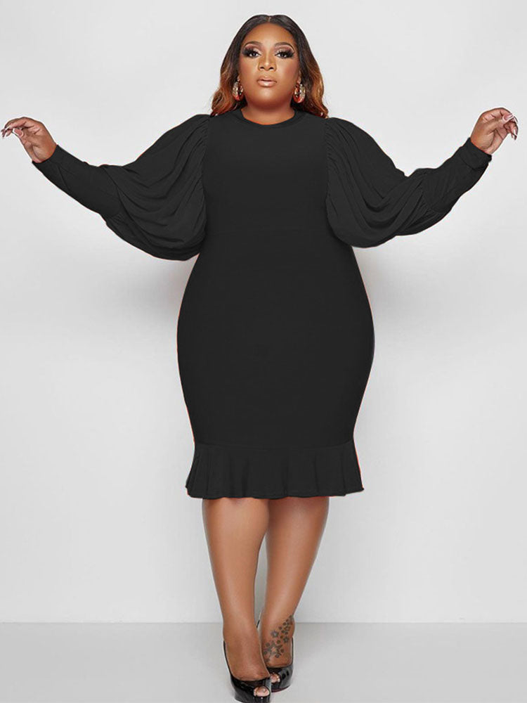 Woman wearing a black dress with puff sleeves and a ruffle hem.