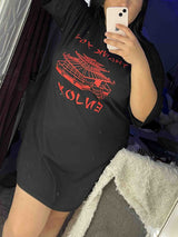Woman taking a mirror selfie in a black t-shirt dress with red graphic print