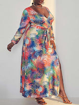 Full body shot of a woman in a vibrant tropical print maxi dress with a high slit, showcasing the flowing fabric.