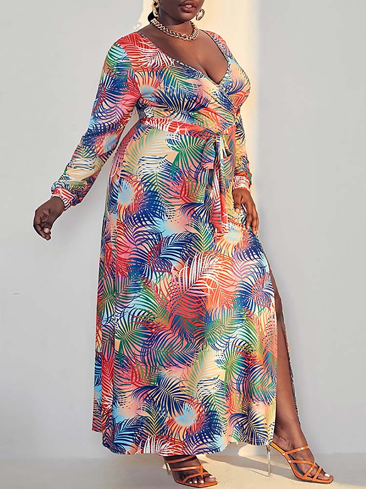 Full body shot of a woman in a vibrant tropical print maxi dress with a high slit, showcasing the flowing fabric.