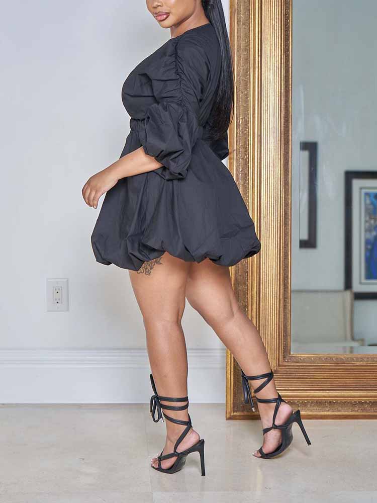 Side view of a woman wearing a black puff sleeve mini dress.
