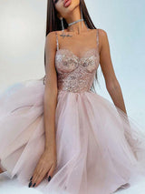 woman in a short pink sequin and tulle party dress sitting