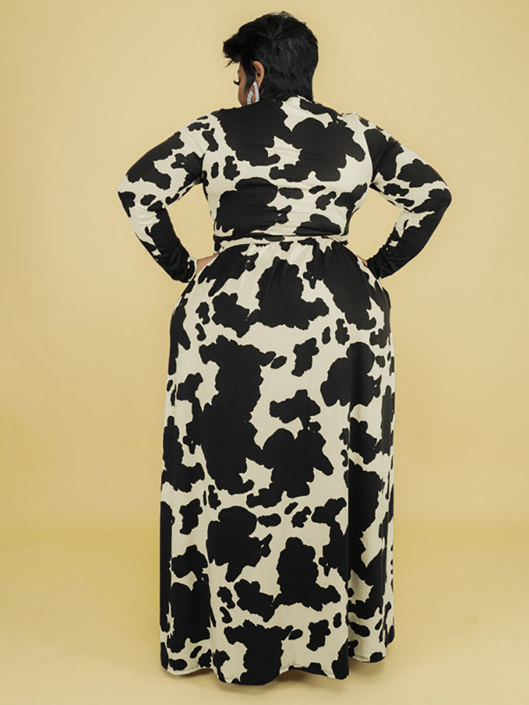 Back view of a woman wearing a black and white cow print maxi dress.