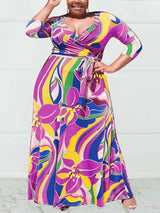 Woman wearing a vibrant purple and yellow abstract floral print maxi dress with 3/4 sleeves and a V-neckline.