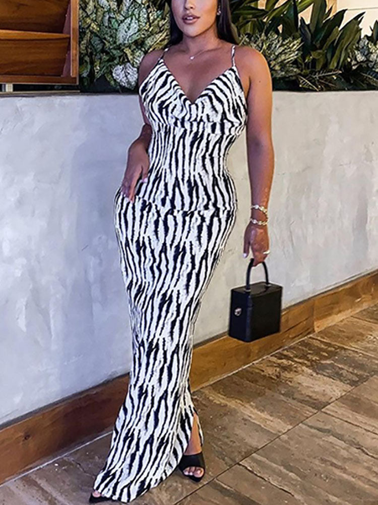 Woman wearing a black and white zebra print maxi dress with spaghetti straps and a side slit