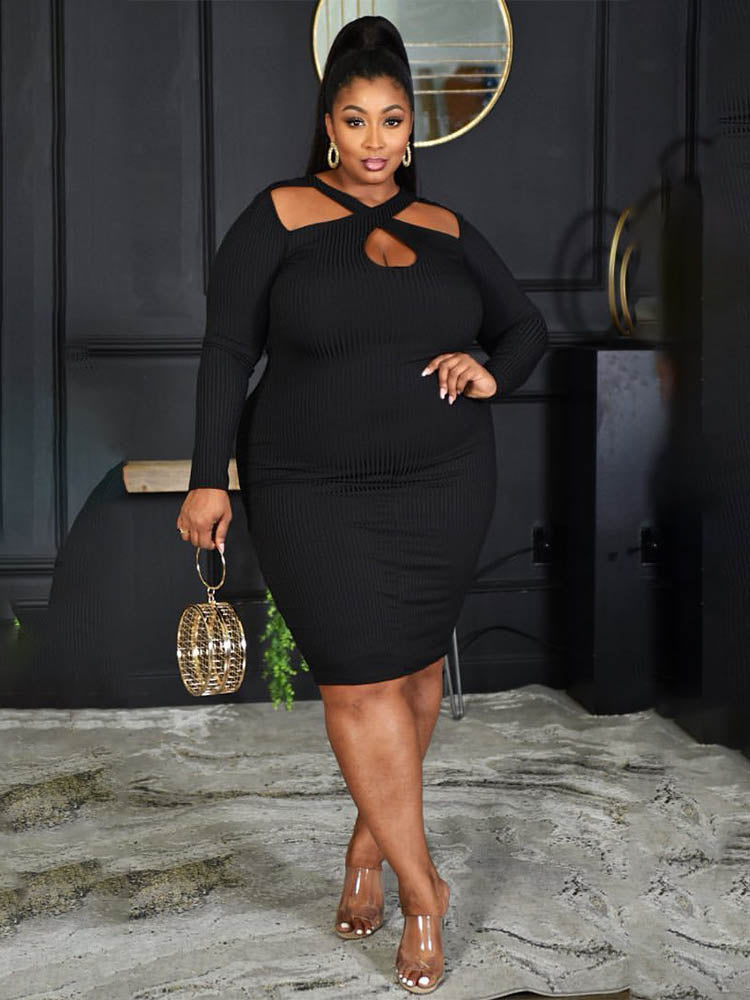Woman wearing a black long-sleeved ribbed knit bodycon dress with a cutout neckline and a gold clutch bag.