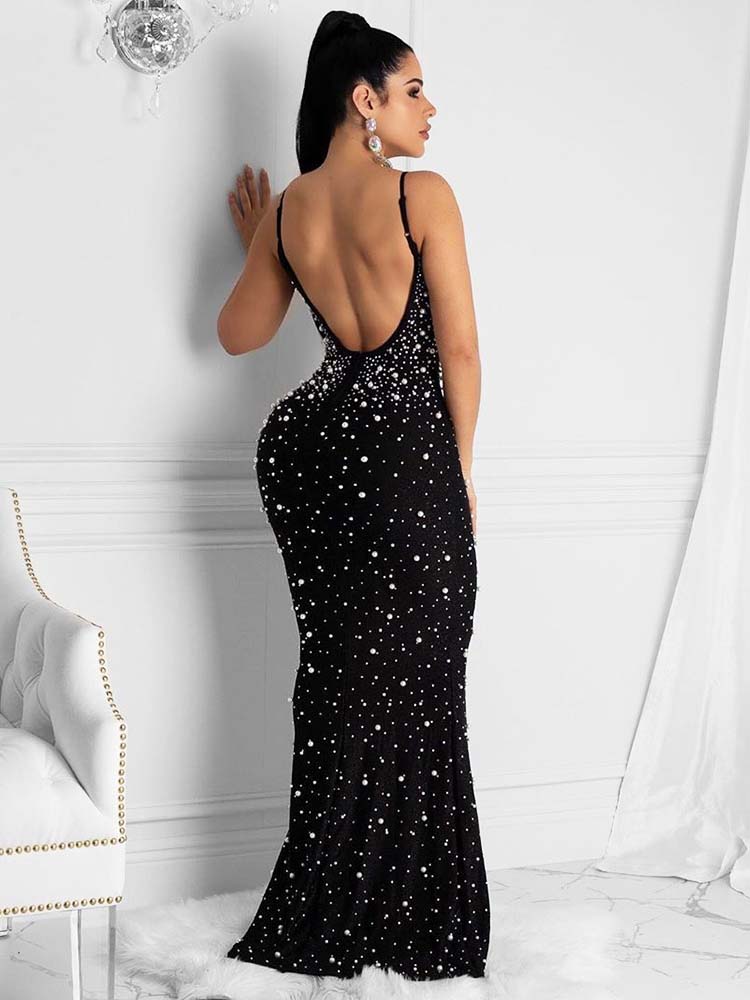 Back view of a woman in a black formal gown with an open back and pearl and rhinestone embellishments.