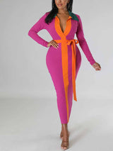 Woman wearing a long-sleeved magenta ribbed midi dress with contrasting orange panels and a matching waist tie.