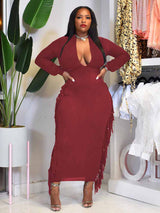 Woman wearing a burgundy maxi dress with fringe detailing and a deep V-neck.