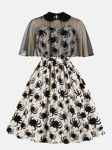 front view of a cream A-line dress with a black spider print and a black mesh capelet overlay