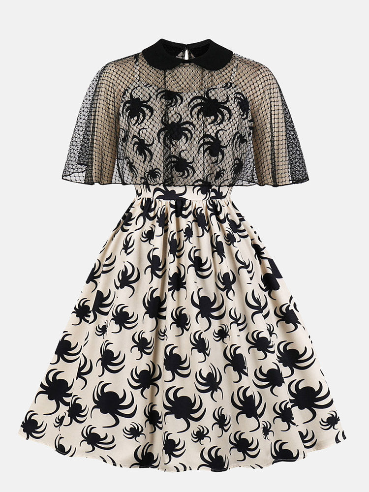 front view of a cream A-line dress with a black spider print and a black mesh capelet overlay