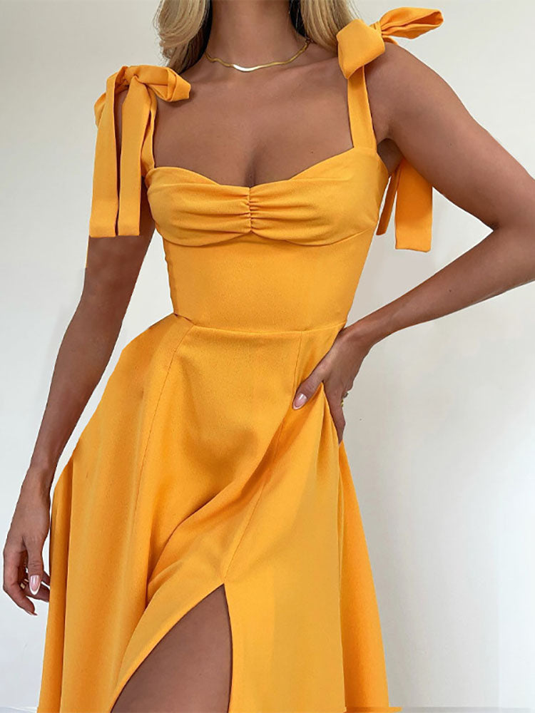 Woman in a yellow ruched bodice dress with tie shoulder straps and a high slit