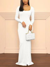 Woman wearing a white ribbed long-sleeve maxi dress and holding a white handbag