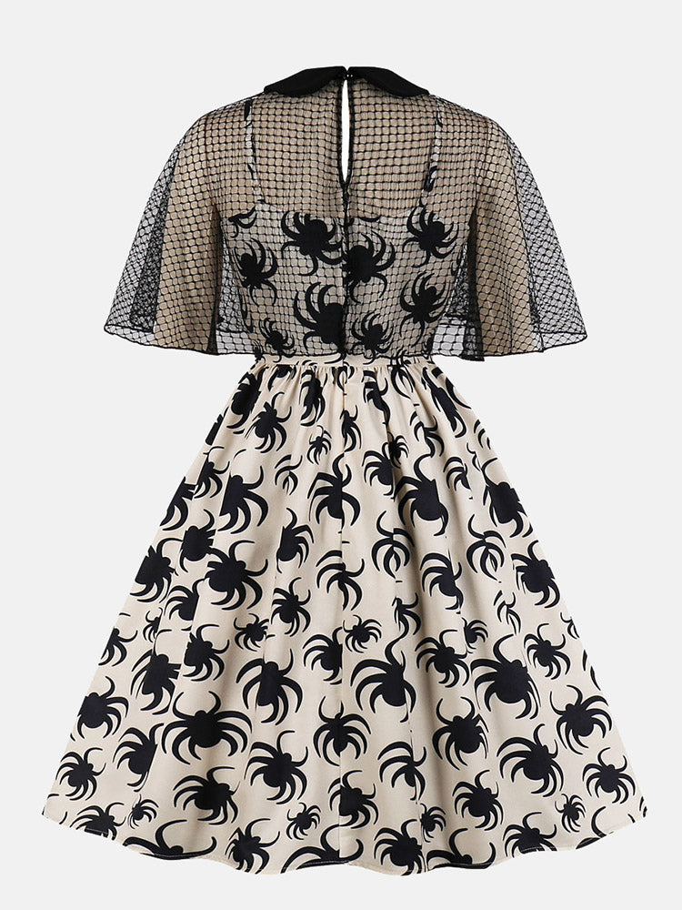 back view of a cream A-line dress with a black spider print and a black mesh capelet overlay
