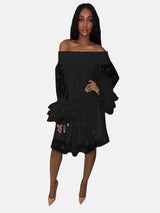 Woman wearing a black off-the-shoulder polka dot dress with ruffled bell sleeves and nude heels