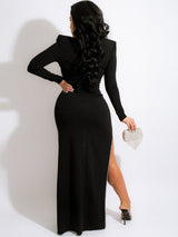 Back view of a woman in a black evening gown with a high slit and long sleeves.