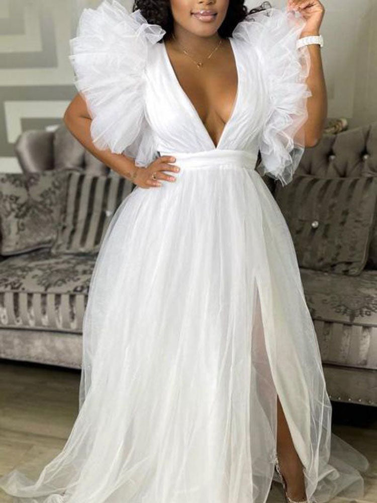 woman in a floor-length white tulle dress with a plunging neckline and dramatic ruffled sleeves