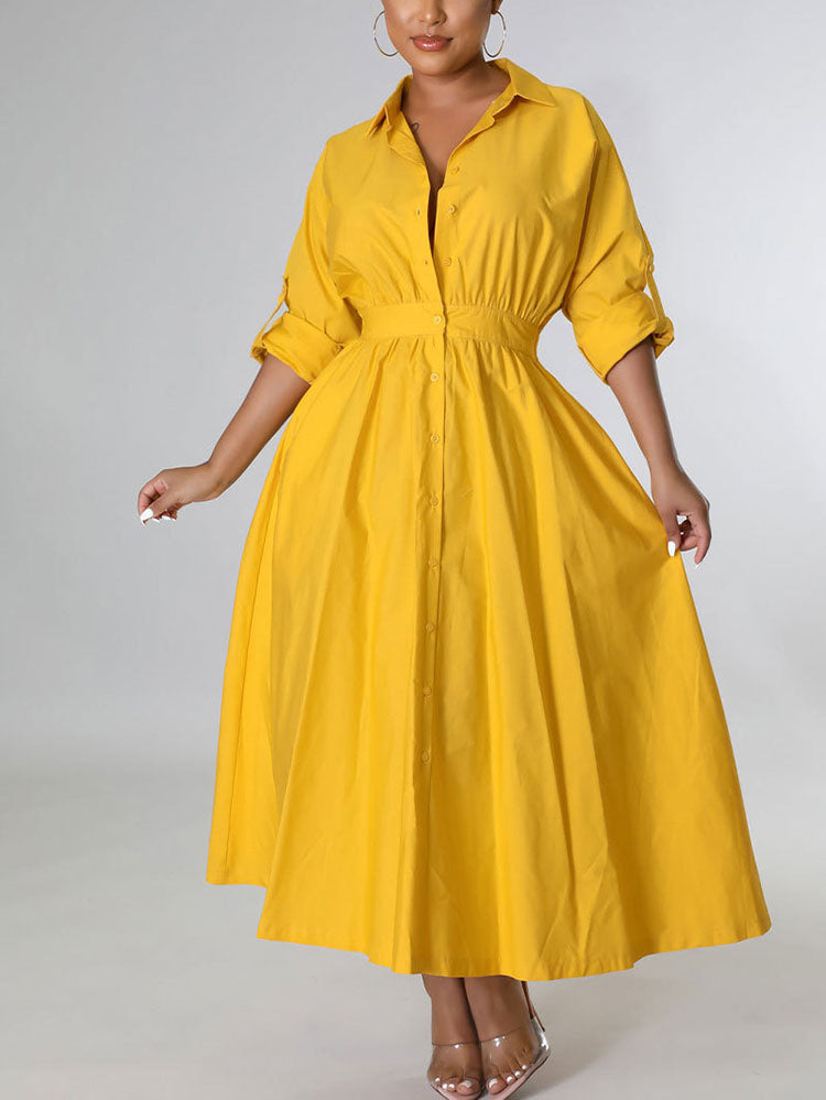 Woman wearing a yellow collared shirt dress with a cinched waist and rolled sleeves.