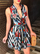 Woman wearing a sleeveless V-neck mini dress with a striped and floral print and tie waist.