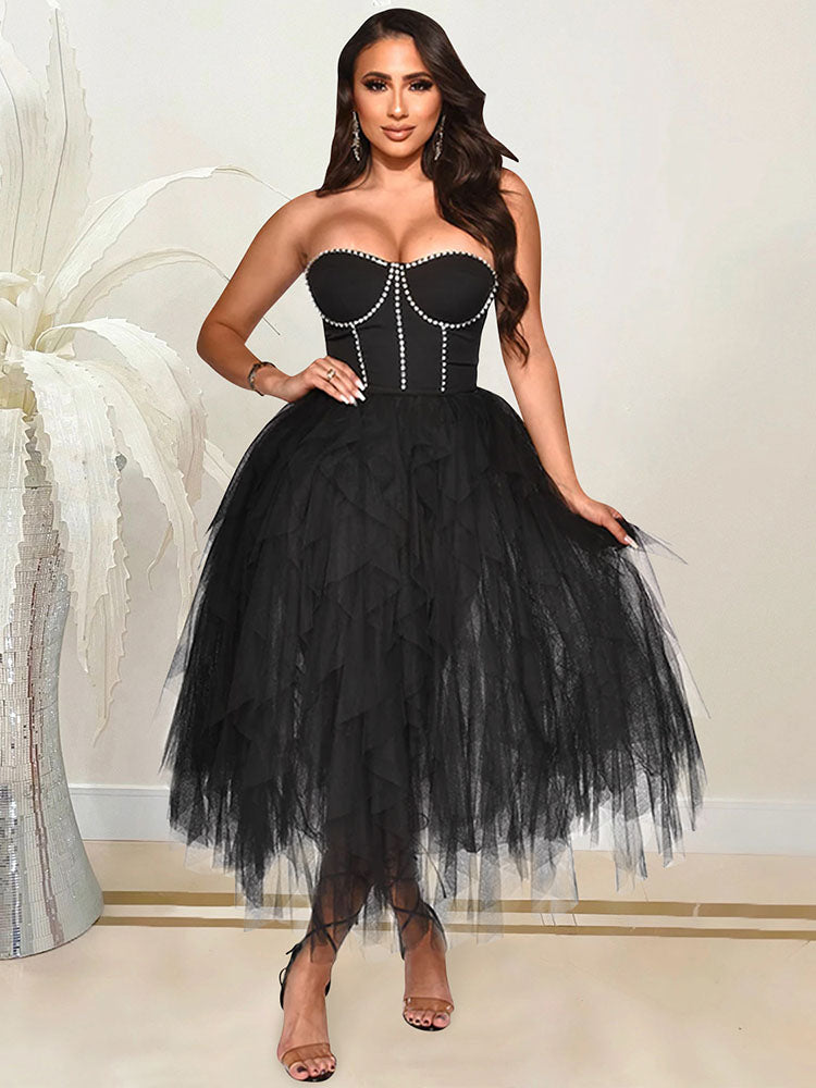 A woman in a black strapless formal dress with a sweetheart neckline and a voluminous tiered tulle skirt.
