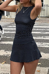 Woman posing in a navy polka dot mini dress on a street.