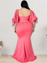Back view of a woman in a coral mermaid gown with puffed sleeves and a zipper closure