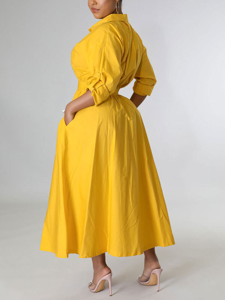 Back view of a woman in a yellow A-line shirt dress with pockets.