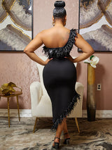 Back view of a woman wearing a black one-shoulder dress with feather trim and an asymmetrical hemline.