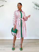Woman wearing a pink and green striped shirt dress with a belted waist and balloon sleeves.