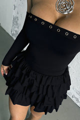 Detail shot of the neckline and ruffled skirt of the black dress.