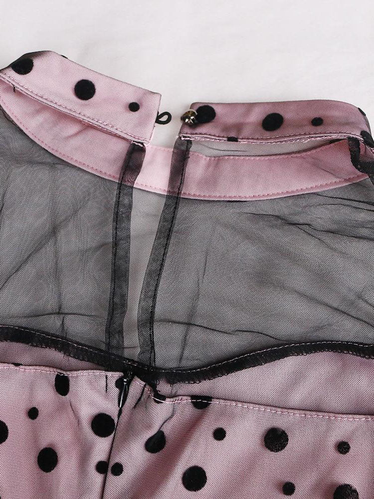 Close-up of the neckline and sheer mesh detail on a pink and black polka dot dress.