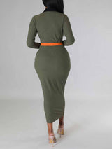 Back view of a woman in a long-sleeved olive green ribbed midi dress with contrasting orange panels.