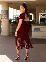 back view of a woman in a burgundy ribbed knit midi dress with cut-out neckline and fringe hem
