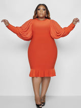 Woman wearing an orange dress with puff sleeves and a ruffle hem.