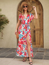 Woman modeling a floral print maxi dress with a high slit.
