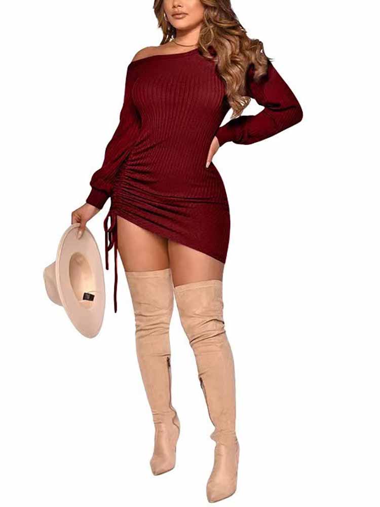Woman in a dark red ribbed knit mini dress with bishop sleeves and a ruched side detail, holding a hat.