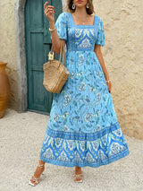 Woman wearing a blue floral print midi dress with puff sleeves and a square neckline.