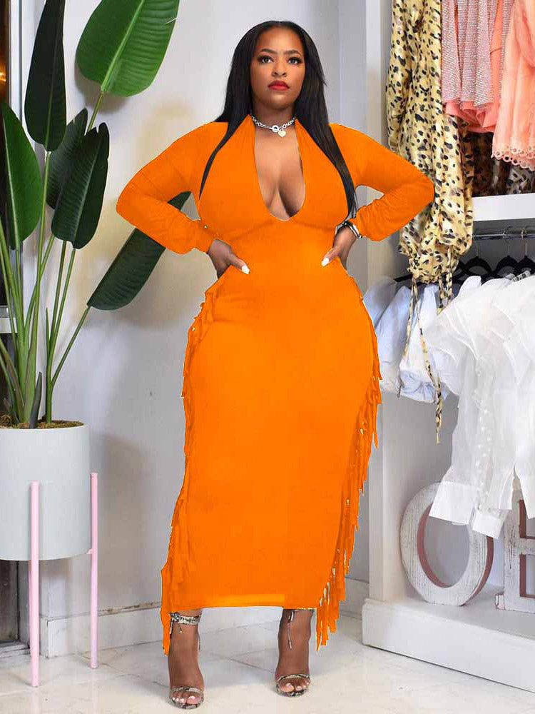 Woman wearing an orange maxi dress with fringe detailing and a deep V-neck.