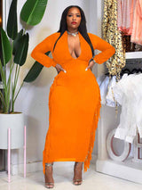 Woman wearing an orange maxi dress with fringe detailing and a deep V-neck.