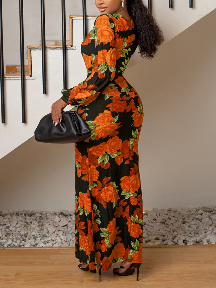 Back view of a woman wearing a long black dress with an orange rose floral print, V-neck, long sleeves, and a high slit.