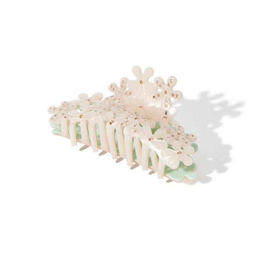 angled view of white floral claw clip with gemstones