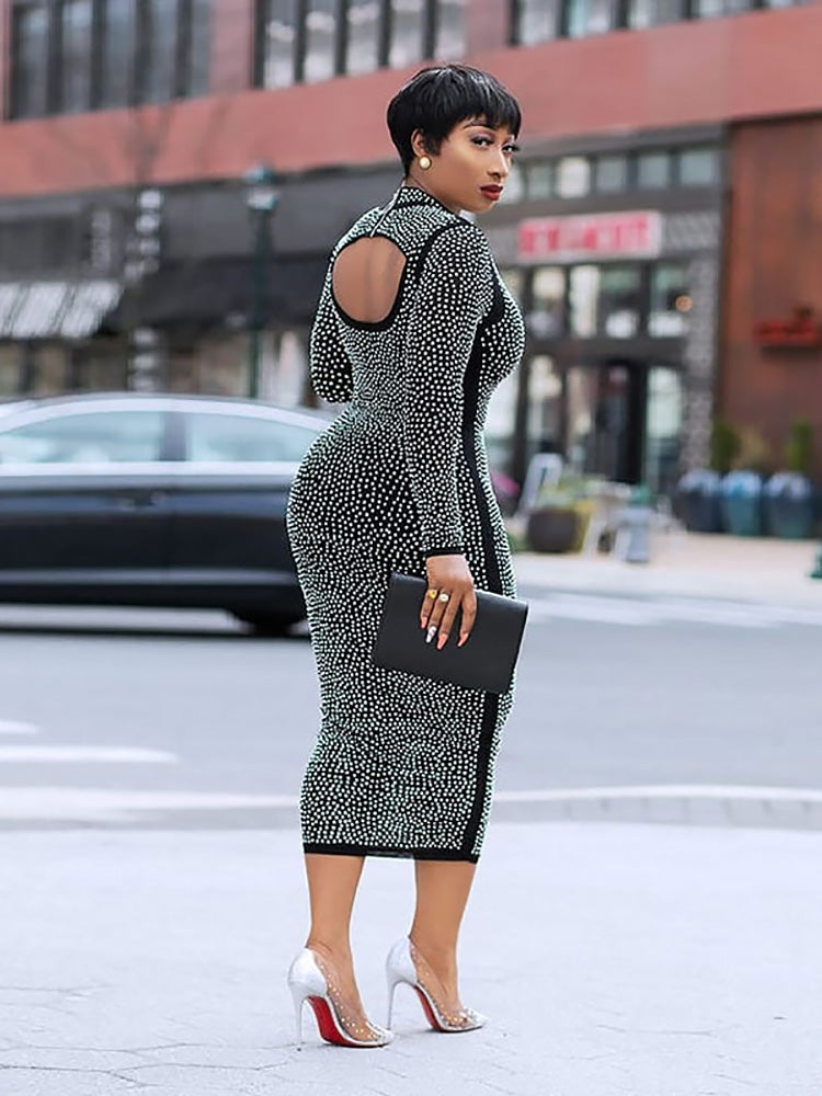 Side view of a woman in a black rhinestone midi dress, showcasing the back cut-out.
